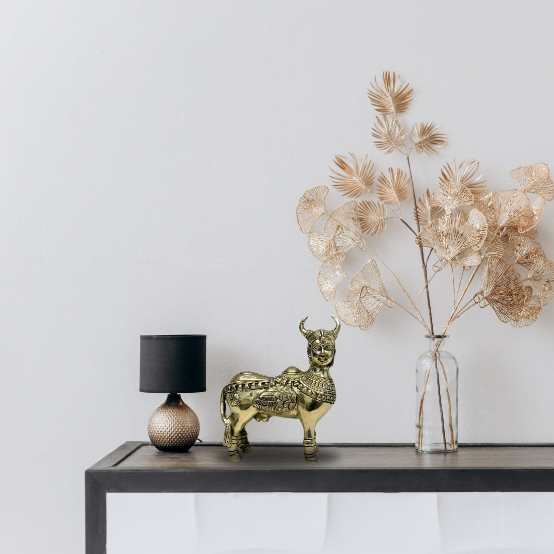 Brass Kamdhenu cow idol displayed on a modern console shelf in a neutral room