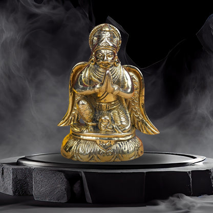 Brass Lord Garud Dev Ji idol displayed on a dark pedestal with incense smoke