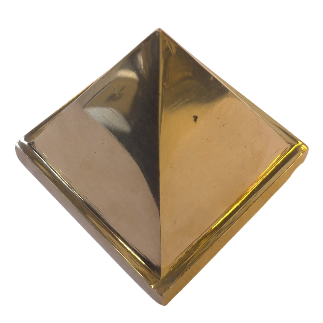High-angle view of solid brass pyramid isolated on white background