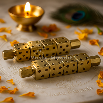 Two brass Ramal Pass divination rods displayed beside a glowing diya