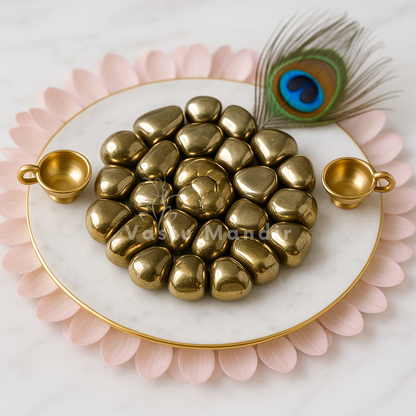 Pyrite tumbled stones displayed in a pink shell dish with gold beads and a peacock feather