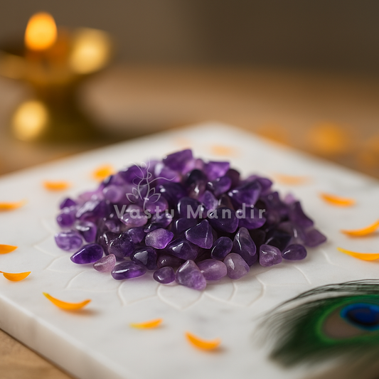 Amethyst crystal chips arranged on a carved white plate with marigold petals and a softly lit diya