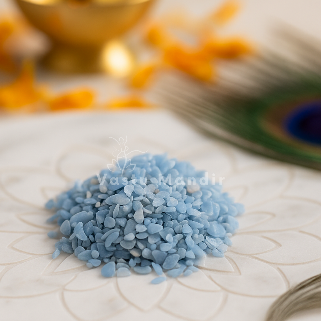 Angled view of angelite crystal chips on a white plate with marigold petals and a peacock feather