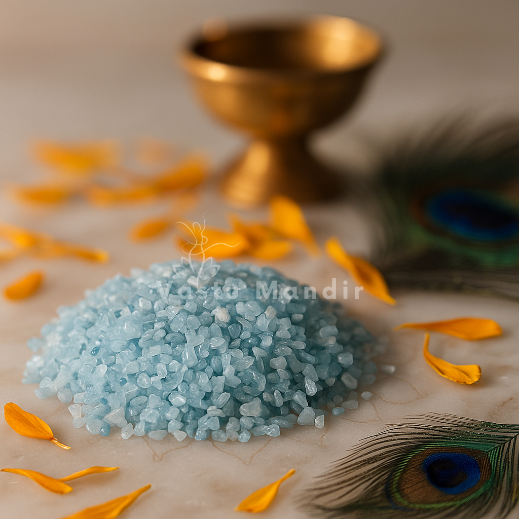 Angled view of aquamarine crystal chips on a white plate with marigold petals and a peacock feather