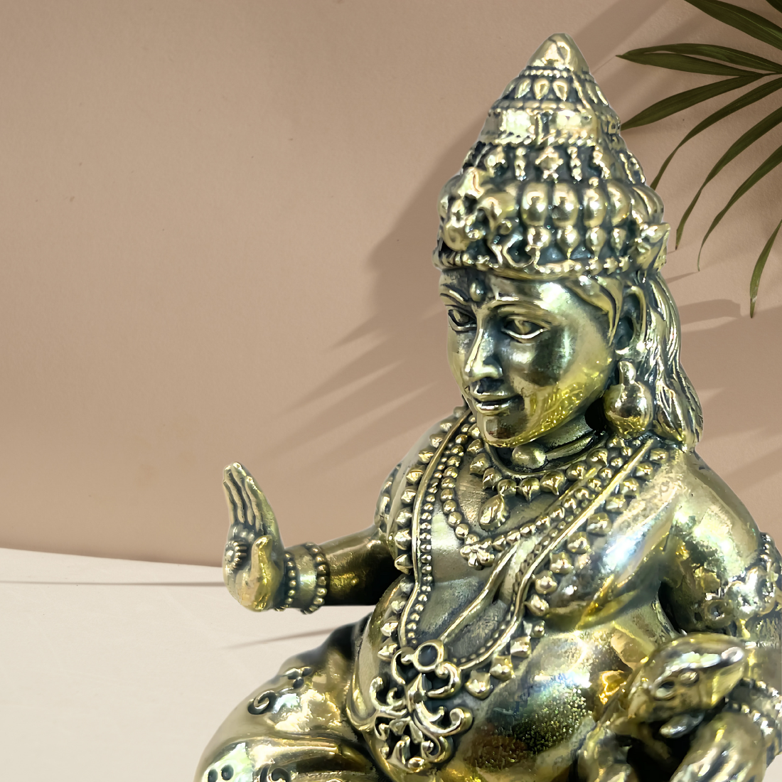 Brass Lord Dhan Kuber Ji idol close-up of the face, crown and raised hand