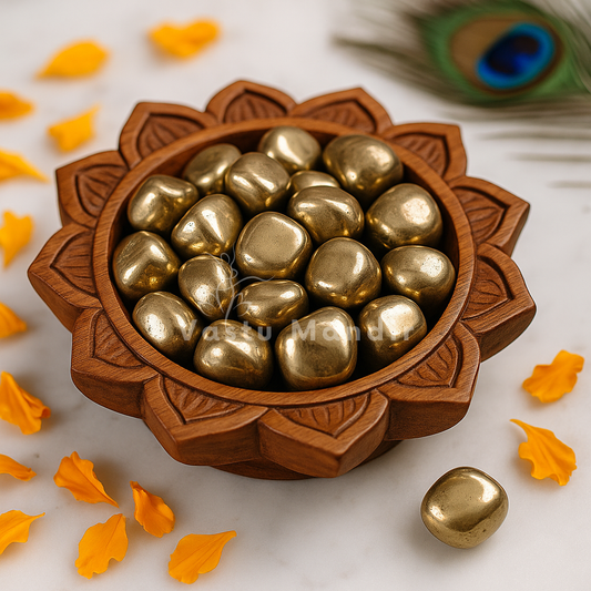 Pyrite tumbled stones arranged on a carved white plate with marigold petals and a softly lit diya