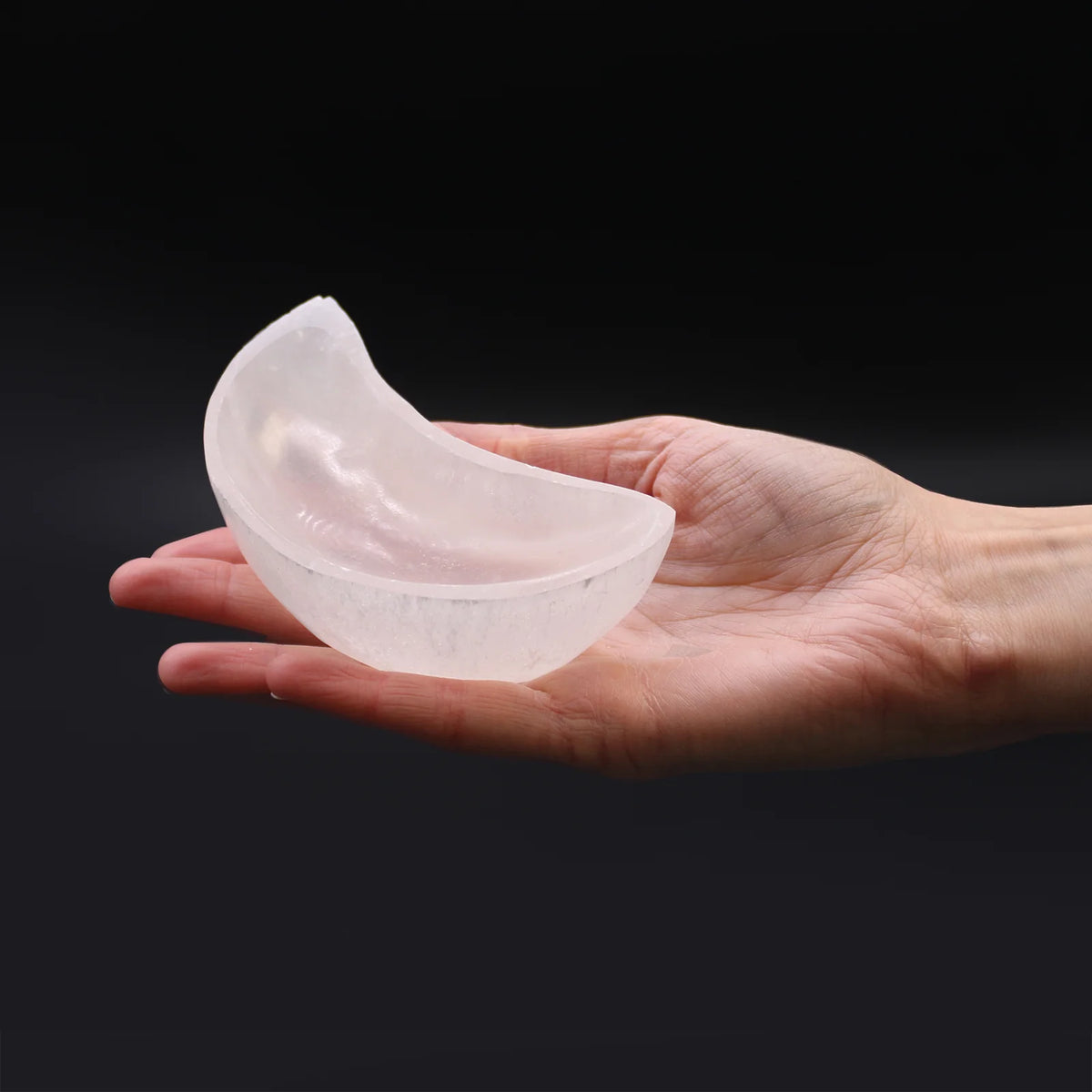 Cresent moon selenite charging bowl shown in a close atmospheric product view