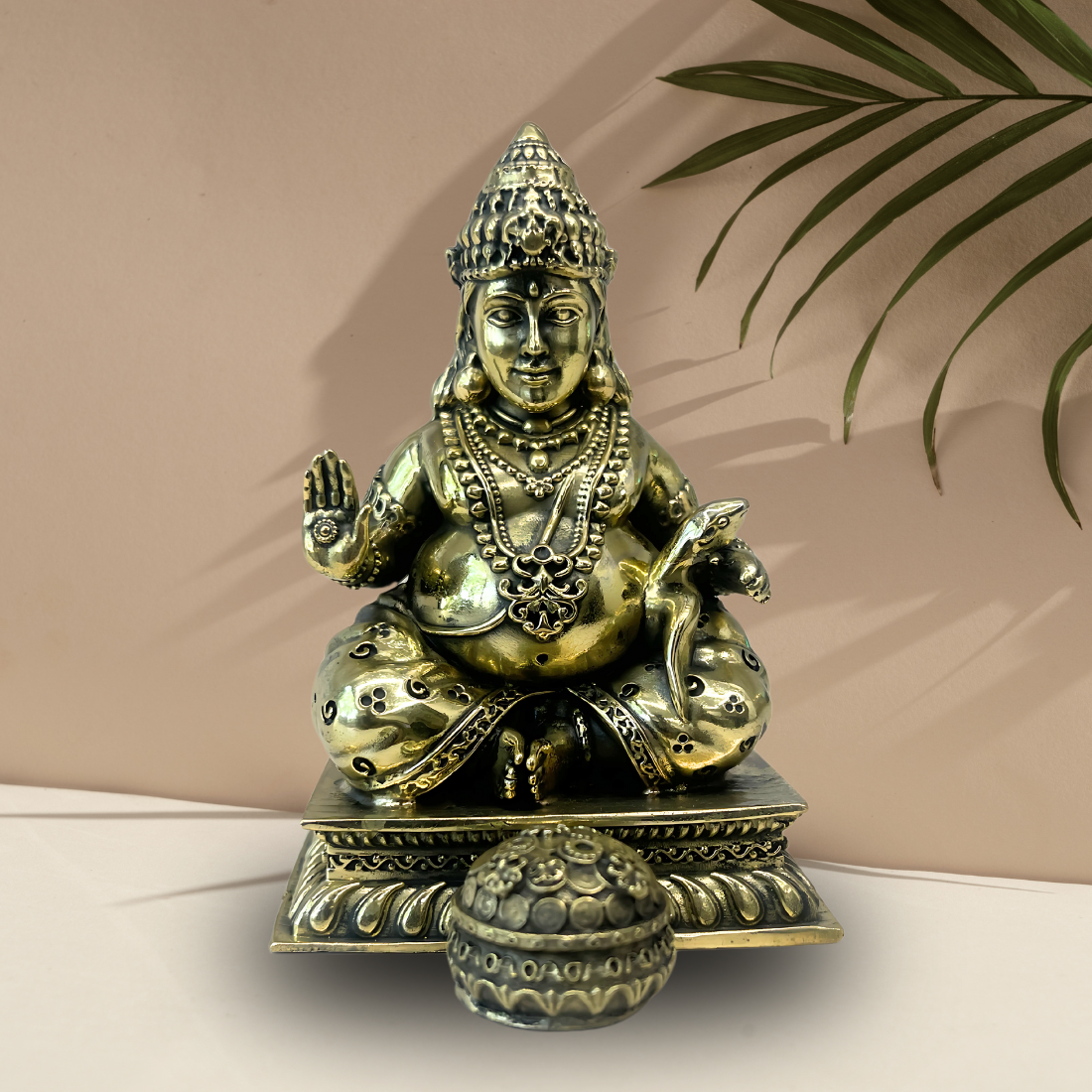 Brass Lord Dhan Kuber Ji idol front three-quarter view on a beige pedestal