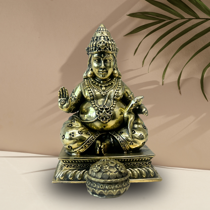 Brass Lord Dhan Kuber Ji idol front three-quarter view on a beige pedestal
