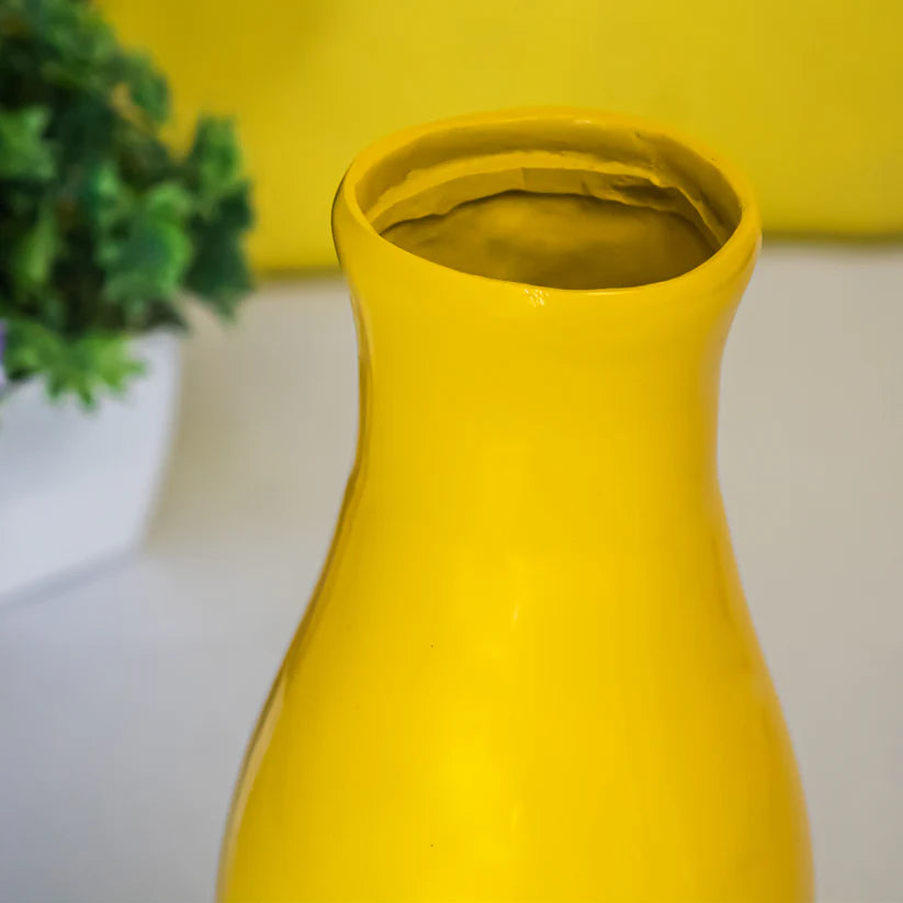 Small yellow decorative resin vase photographed from a side angle