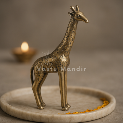 Brass giraffe idol on a round stone plate against a warm studio background