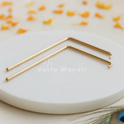 Brass L-shaped dowsing rod pair displayed on a light sacred plate
