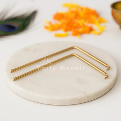Angled brass L-rod pair arranged on a white marble surface