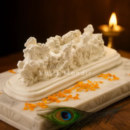 Twelve white running horses resin sculpture displayed with marigold petals and a lit brass diya