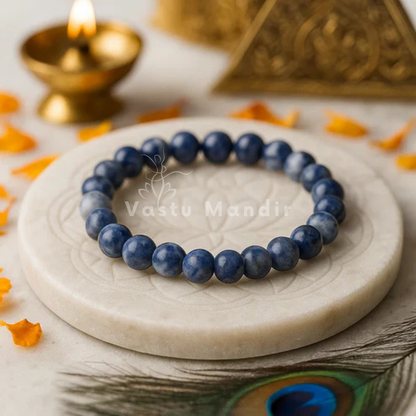 100% Natural Sodalite beads with deep blue color and white veining on a marble surface with decorative elements in the background