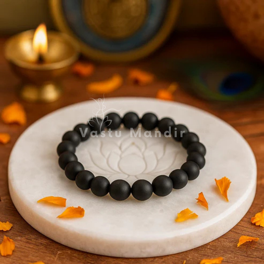 100% Natural Sulemani beads with distinctive black color and natural banding patterns on a white marble coaster with Diwali decorations in the background