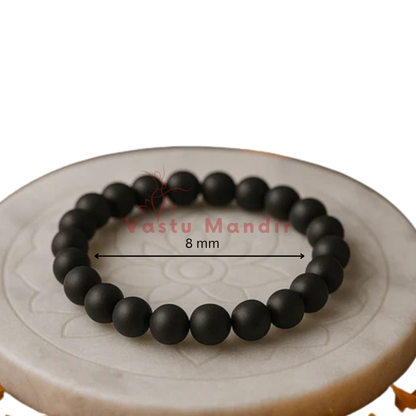 100% Natural Sulemani beads with distinctive black color and natural banding patterns on a decorative plate with 'Vastu Mandir' branding and measurement label.