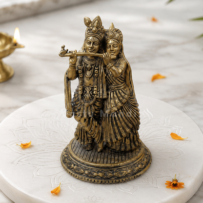 Brass Radha Krishna idol on a sacred marble plate with floral accents