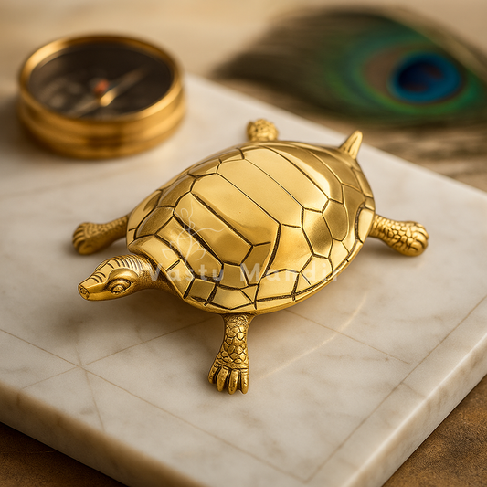 Large pure brass tortoise idol on a tiled sacred surface with peacock feather and diya