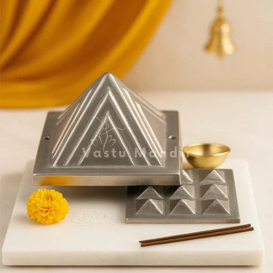 Two lead pyramid layers displayed separately on a marble platform with a marigold flower and incense sticks