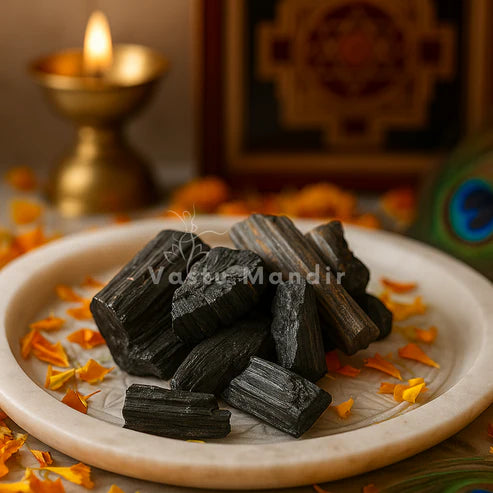 Rough black tourmaline rods and chunks displayed on a decorated white plate