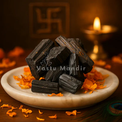 Black tourmaline rods stacked on a white plate in a softly lit traditional setting