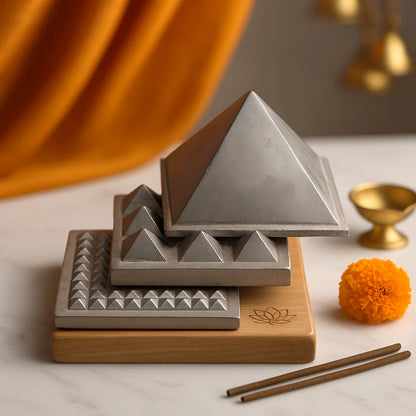 3-layer zinc Vastu pyramid displayed on a wooden base with marigold flowers and brass diya