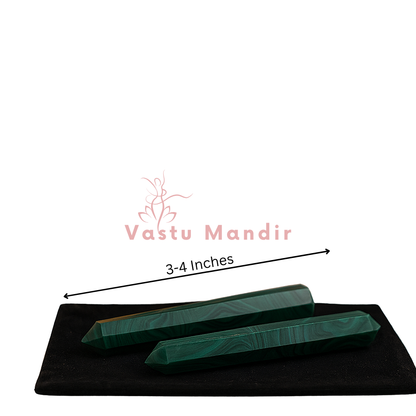 Two malachite crystal pencils presented on a black base against a white background