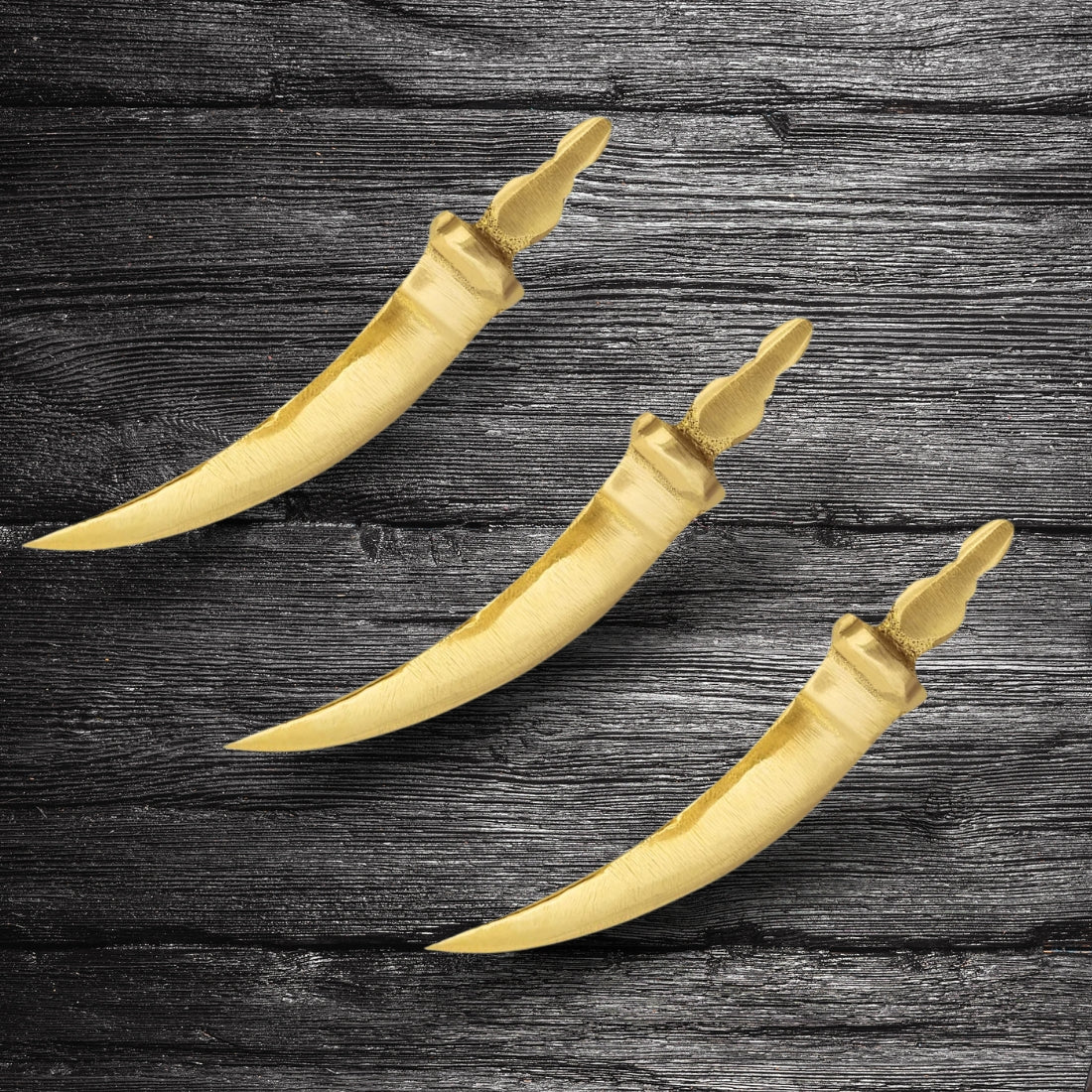 Curved brass talwar miniature three brass talwar miniatures arranged on dark wood