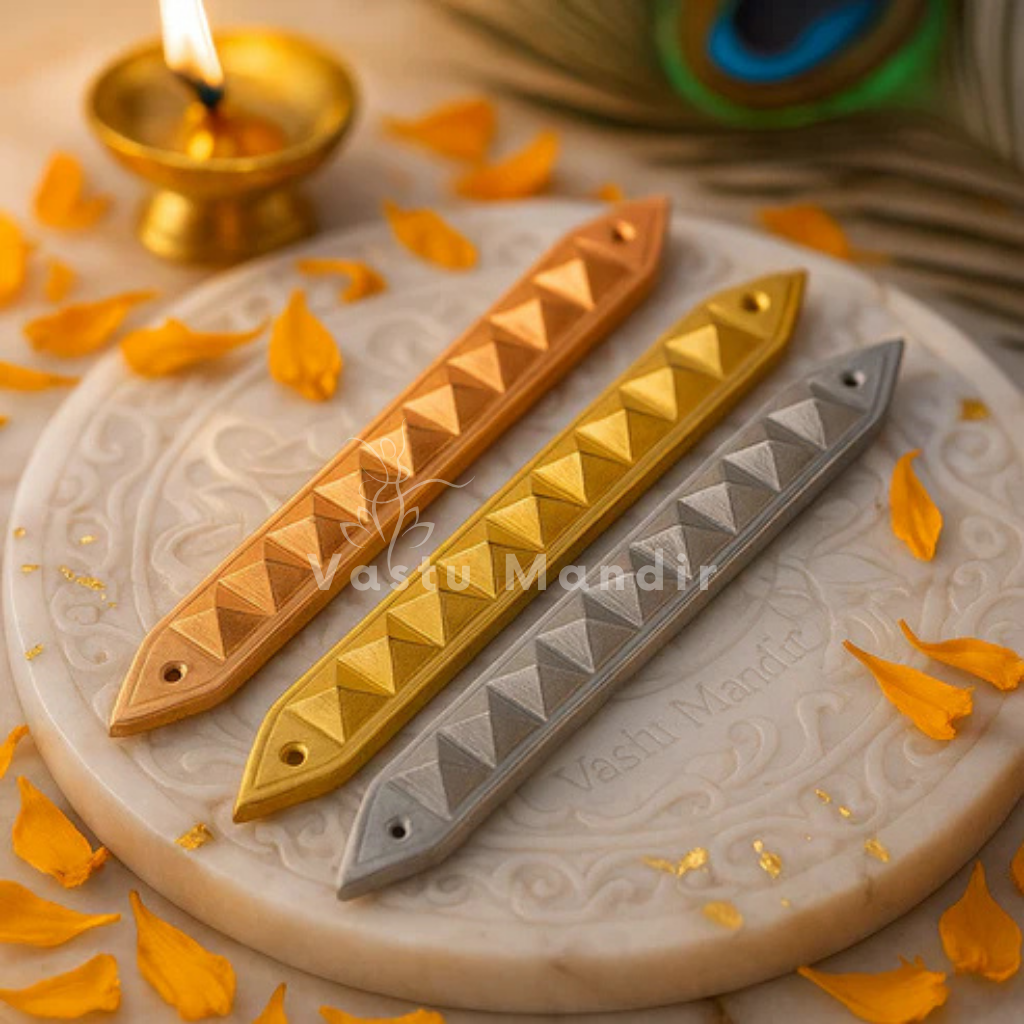 Three metallic bar accessories in Copper, brass, and Lead on a textured surface with a lit candle in the background.