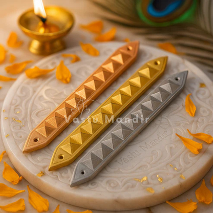 Three metallic bar accessories in Copper, brass, and Lead on a textured surface with a lit candle in the background.