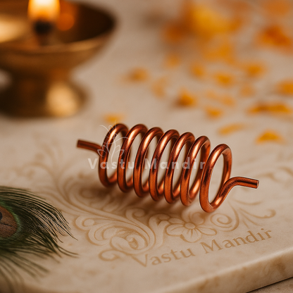 Copper Vastu spring displayed on an engraved stone surface