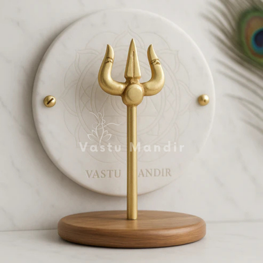 Brass Trishul idol standing on a wooden base against a white marble disc