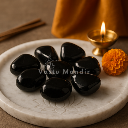Angled view of polished black tourmaline stones on a decorated white plate