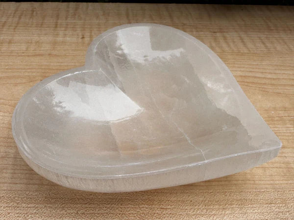 Heart shaped selenite charging bowl presented in a second hand-held view