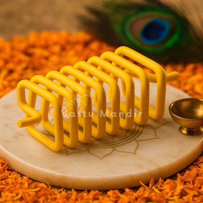 Yellow square Vastu spring displayed on a marble plate with marigold petals