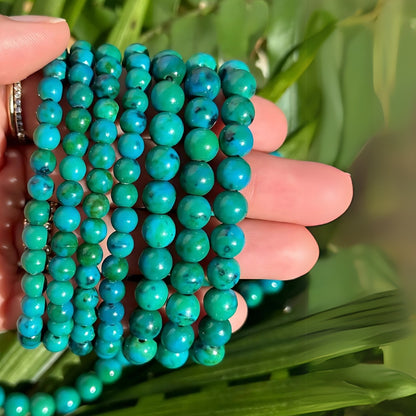 Chrysocolla crystal bracelet displayed in a dark, softly lit spiritual setting