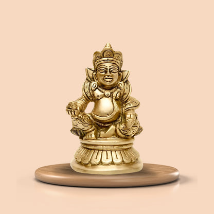 Brass Kuber Ji idol displayed on a round pedestal against a peach background