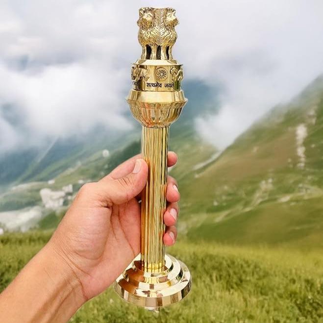 Brass Ashoka Pillar idol held in hand outdoors for scale reference