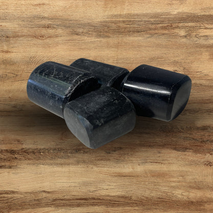 Three raw black tourmaline rods resting on a wooden surface
