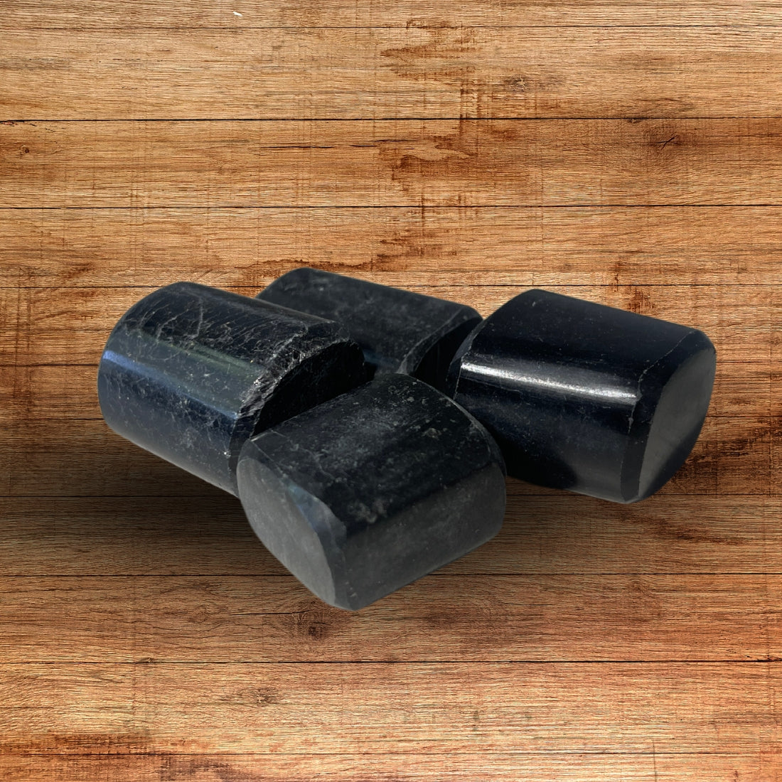 Close view of three raw black tourmaline rods on a wooden surface