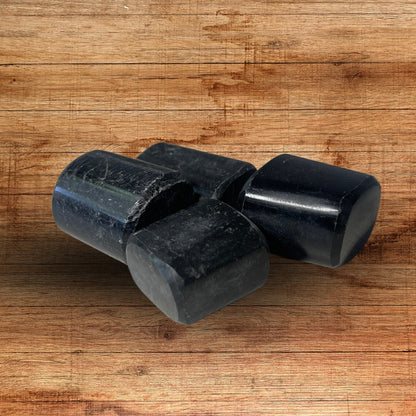 Close view of three raw black tourmaline rods on a wooden surface