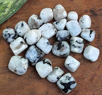 Small white and grey moonstone chips spread on a brown surface