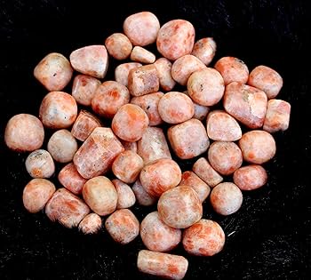 Sunstone tumbled stones arranged against a dark background for a close product view