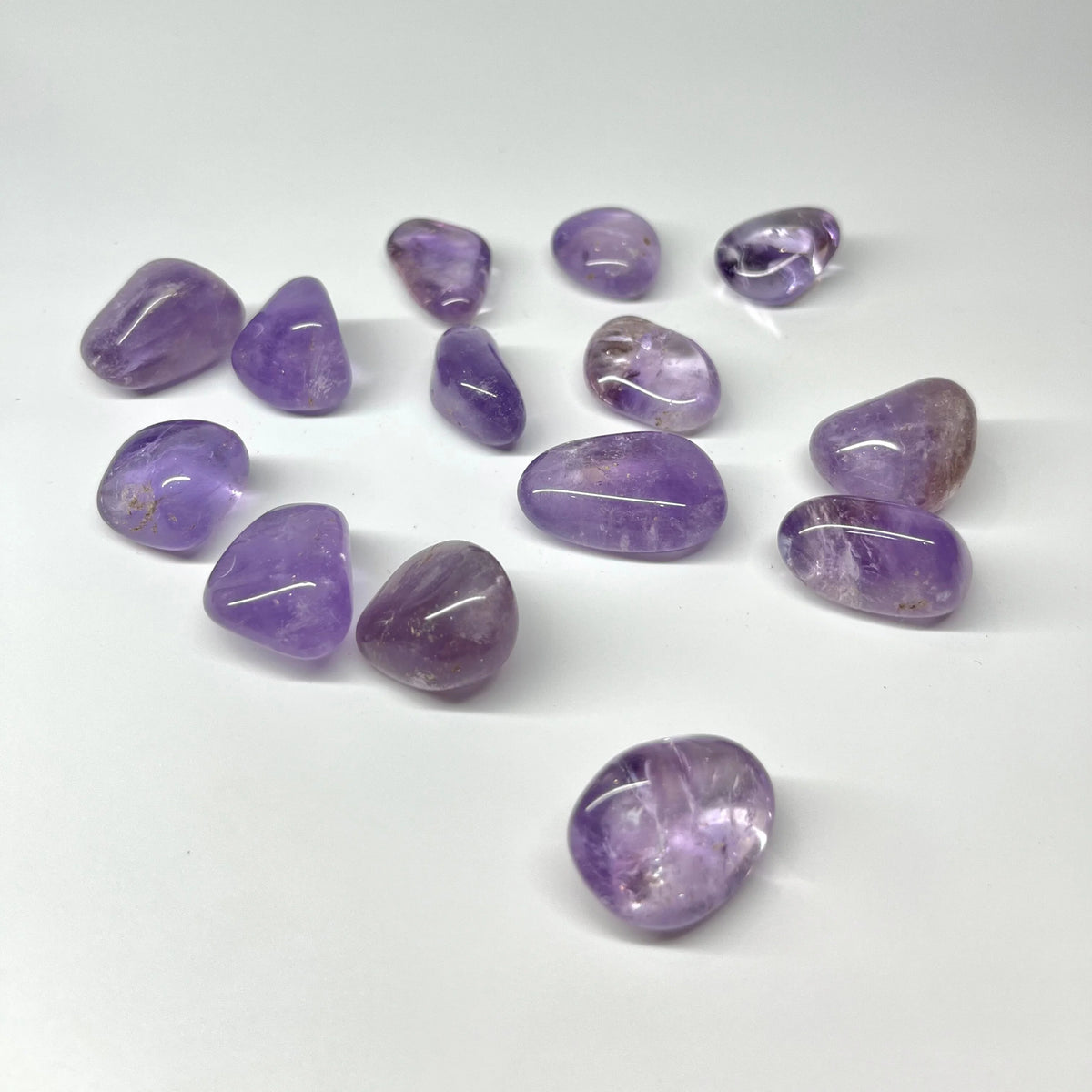 Loose small amethyst stones spaced across a clean white surface