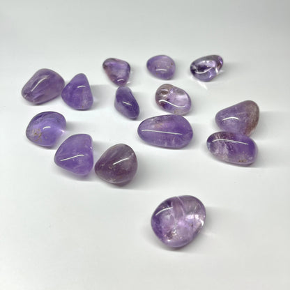 Loose small amethyst stones spaced across a clean white surface