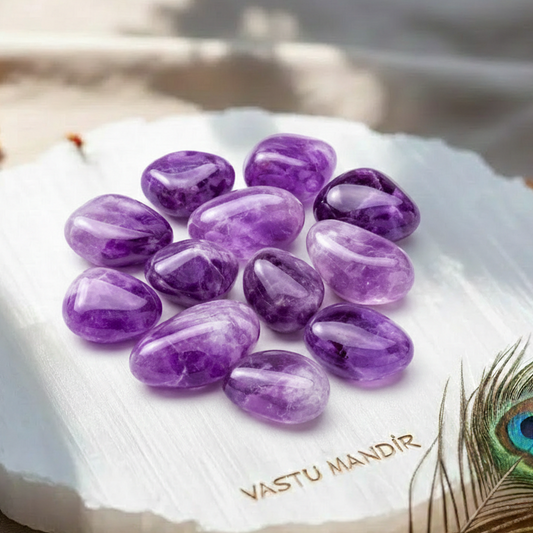 Polished purple amethyst stones arranged on a white selenite plate in soft natural light