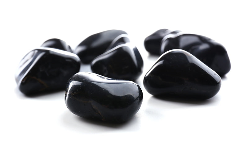 Small group of polished black onyx stones isolated on a pale background