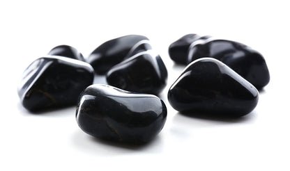 Small group of polished black onyx stones isolated on a pale background