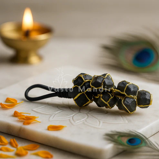 Black Tourmaline Chunk on a decorative surface with peacock feathers and a lit candle in the background.